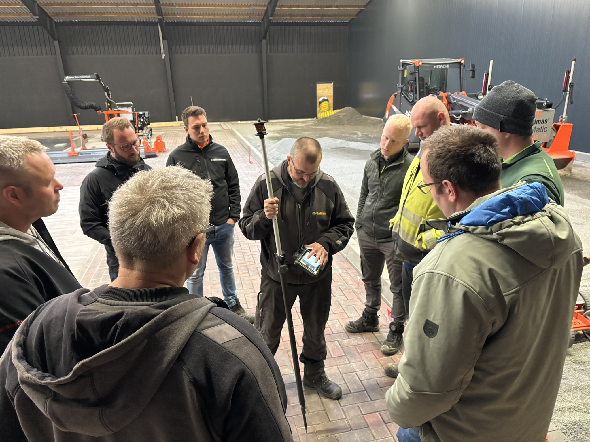 Eine Gruppe von Fachleuten versammelte sich um einen Trainer, der die Ausrüstung in einem Workshop-Umfeld vorführte – Optimas.