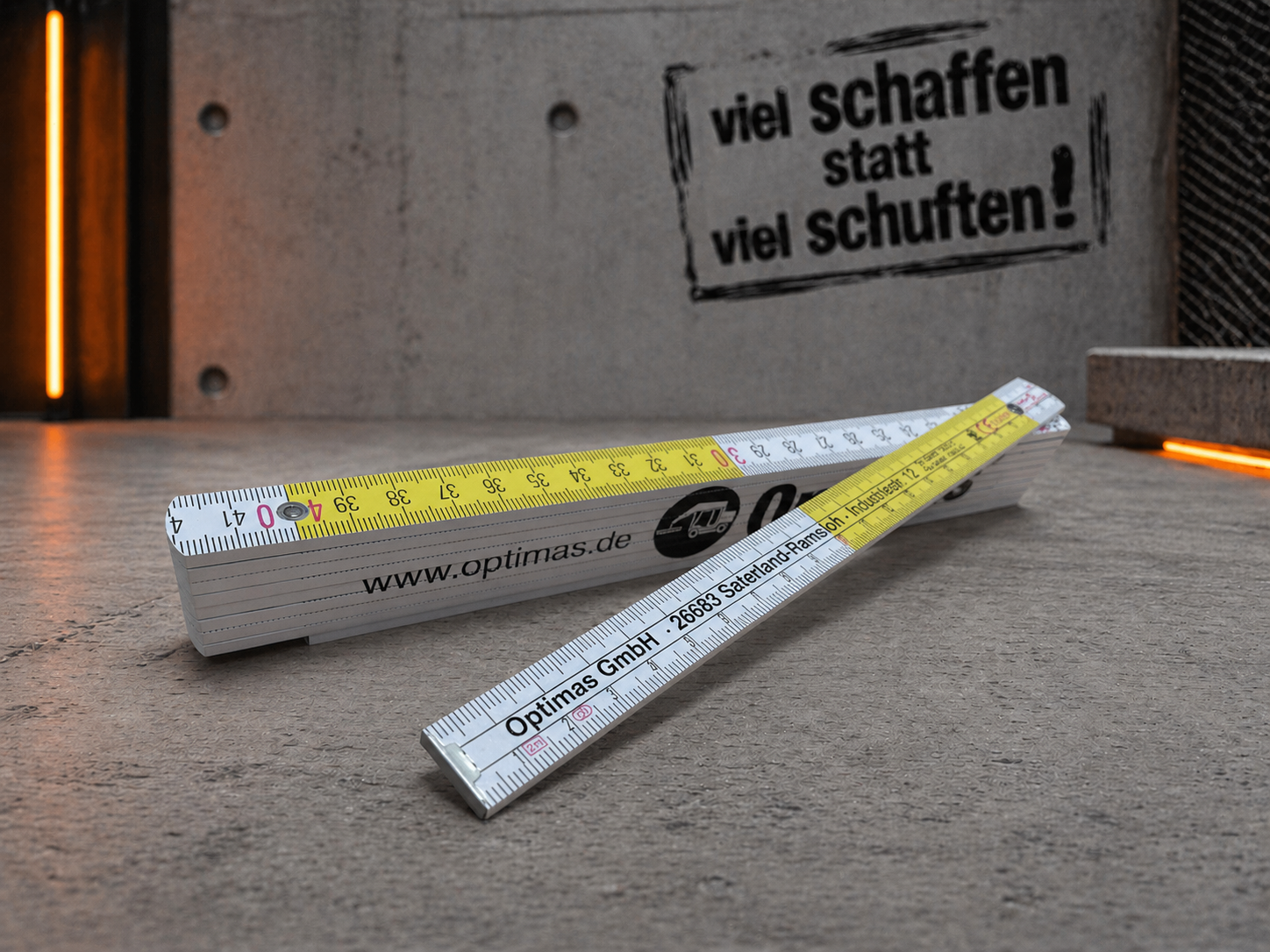 Zwei Maßbänder werden auf einer Betonoberfläche angezeigt, mit einem motivierenden Zitat im Hintergrund – Optimas.