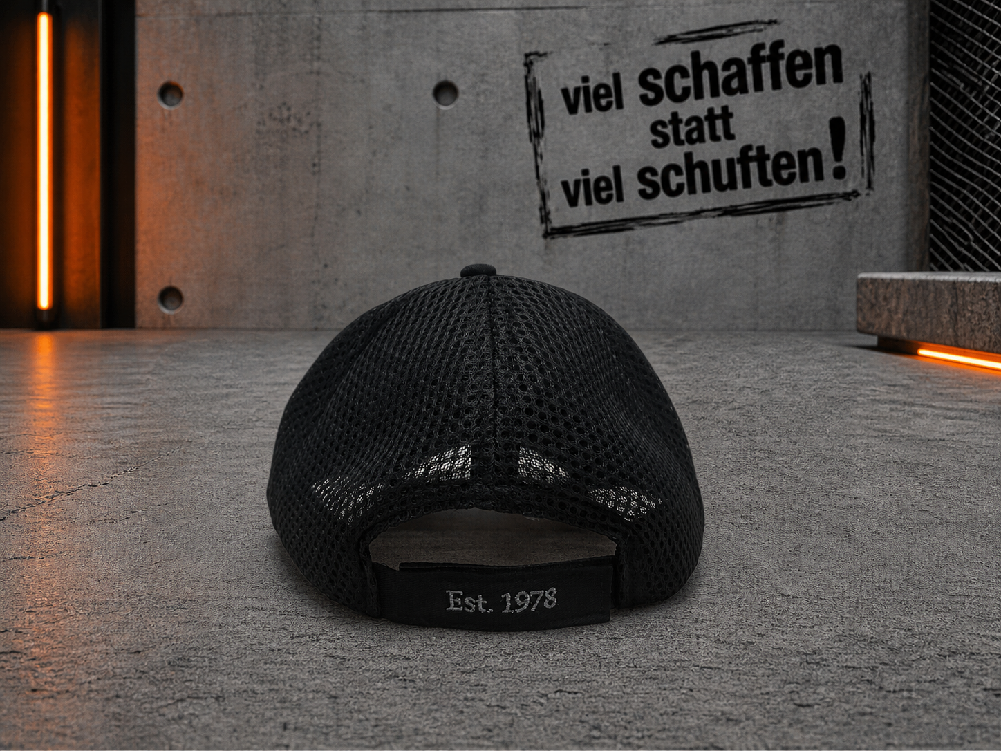 Eine schwarze Netzkappe vor einem strukturierten Hintergrund mit Motivationstext – Optimas.