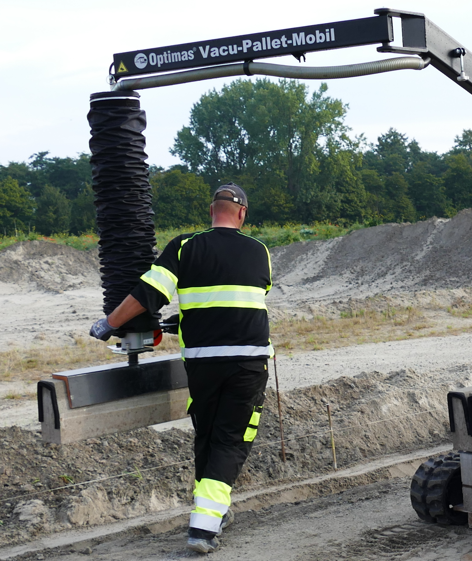 Ein Arbeiter hebt mit einem Optimas Vacu-Pallet-Mobil eine Betonplatte auf einer Baustelle an – Optimas.