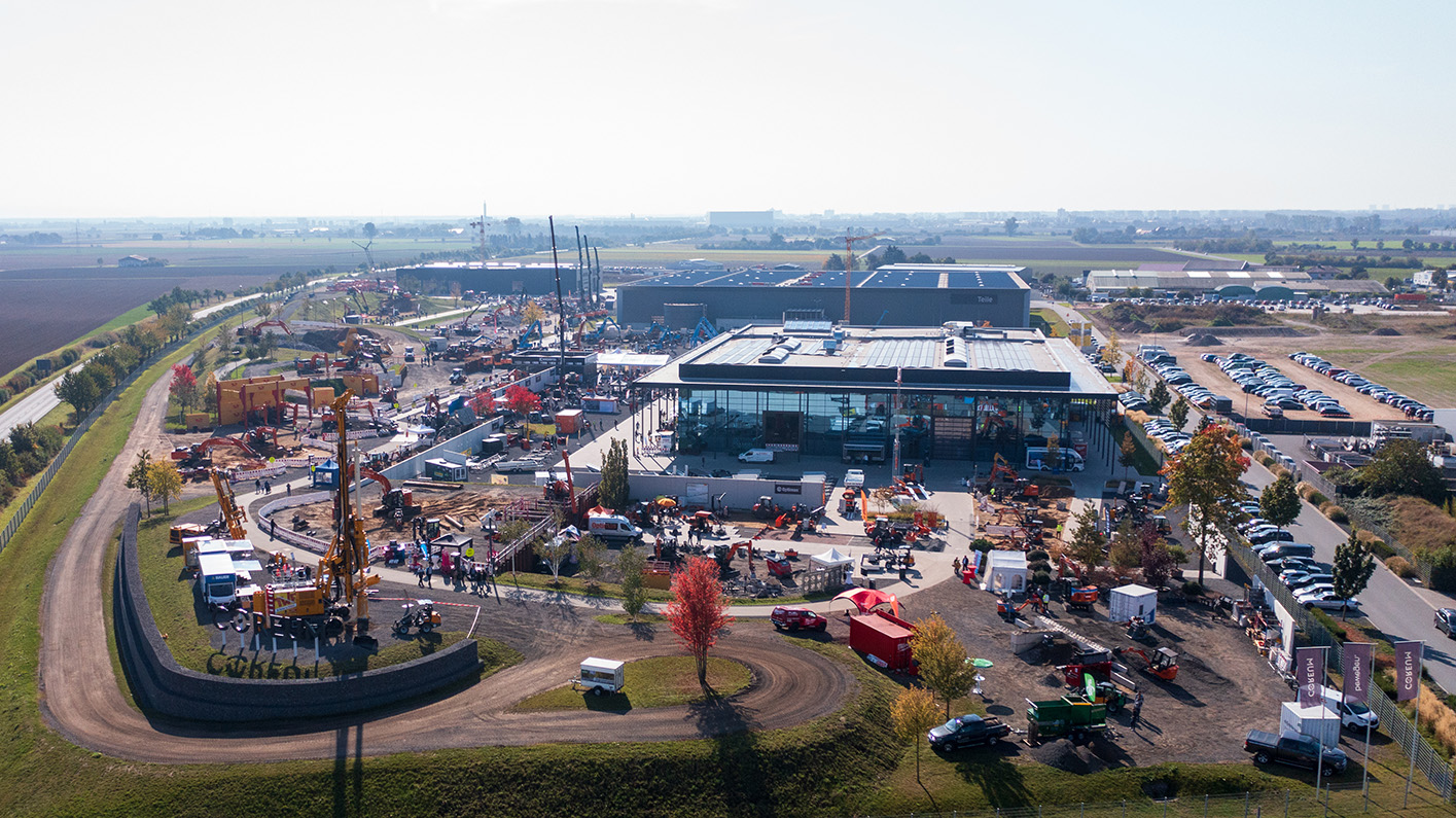 Luftaufnahme einer Großbaustelle mit Gebäuden, Fahrzeugen und Geräten umgeben von Feldern – Optimas