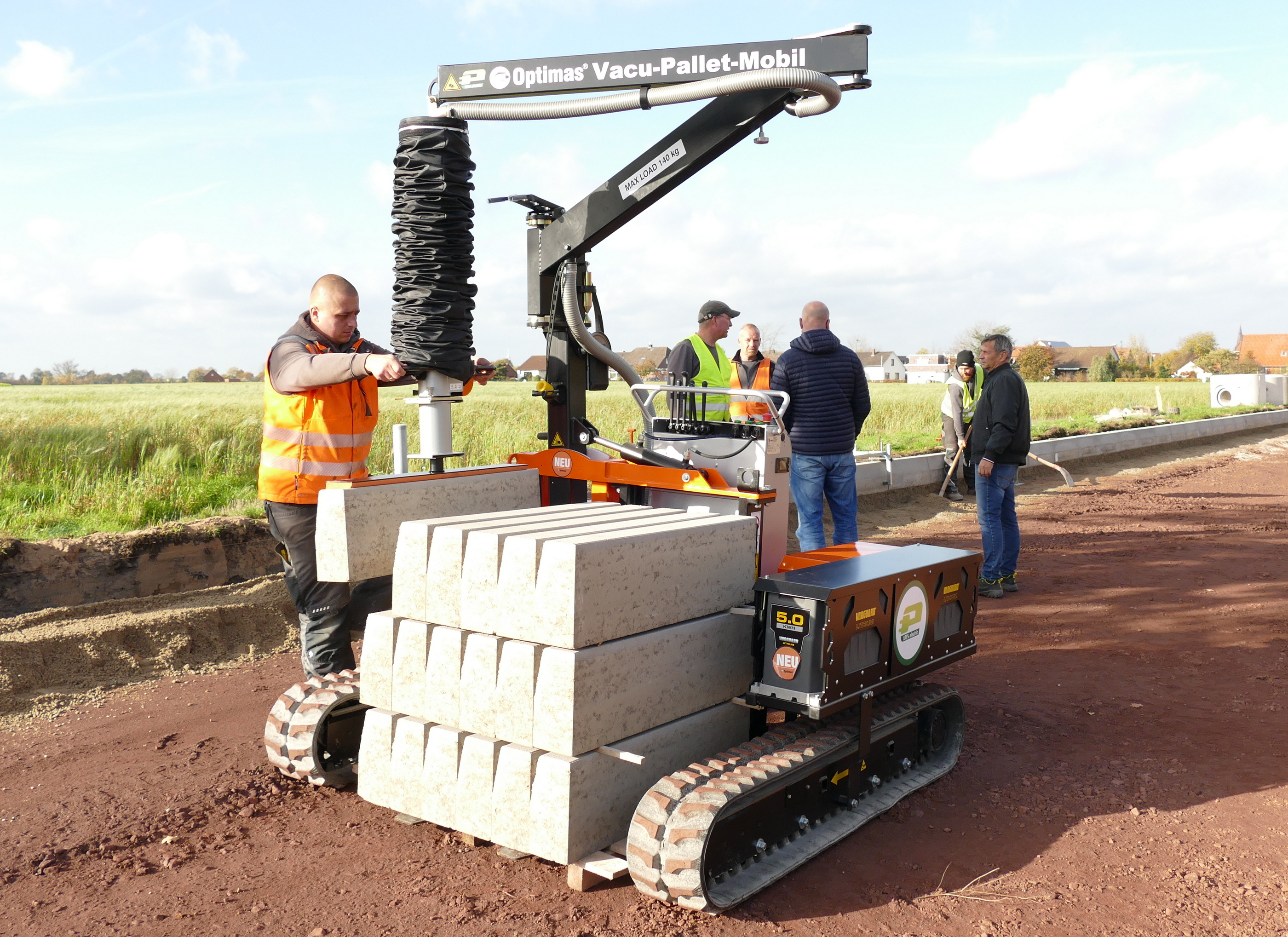 Optimas Vacu-Pallet-Mobil hebt Betonblöcke unter beobachtenden Arbeitern und demonstriert die Funktionalität der Ausrüstung auf einer Baustelle – Optimas.