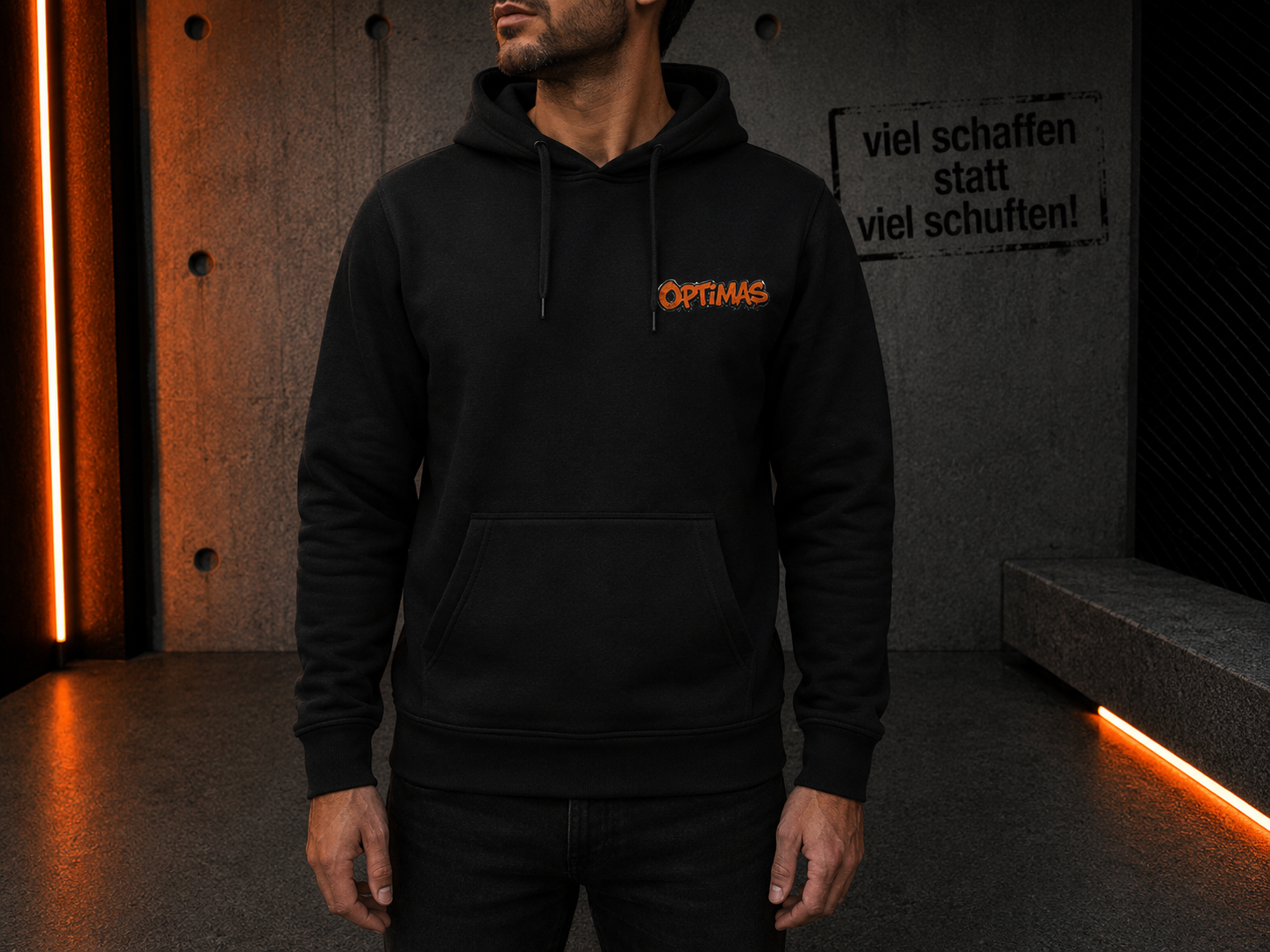 Ein Mann, der einen schwarzen Kapuzenpullover mit dem Aufdruck „Optimas“ trägt und in einer städtischen Umgebung steht – Optimas.