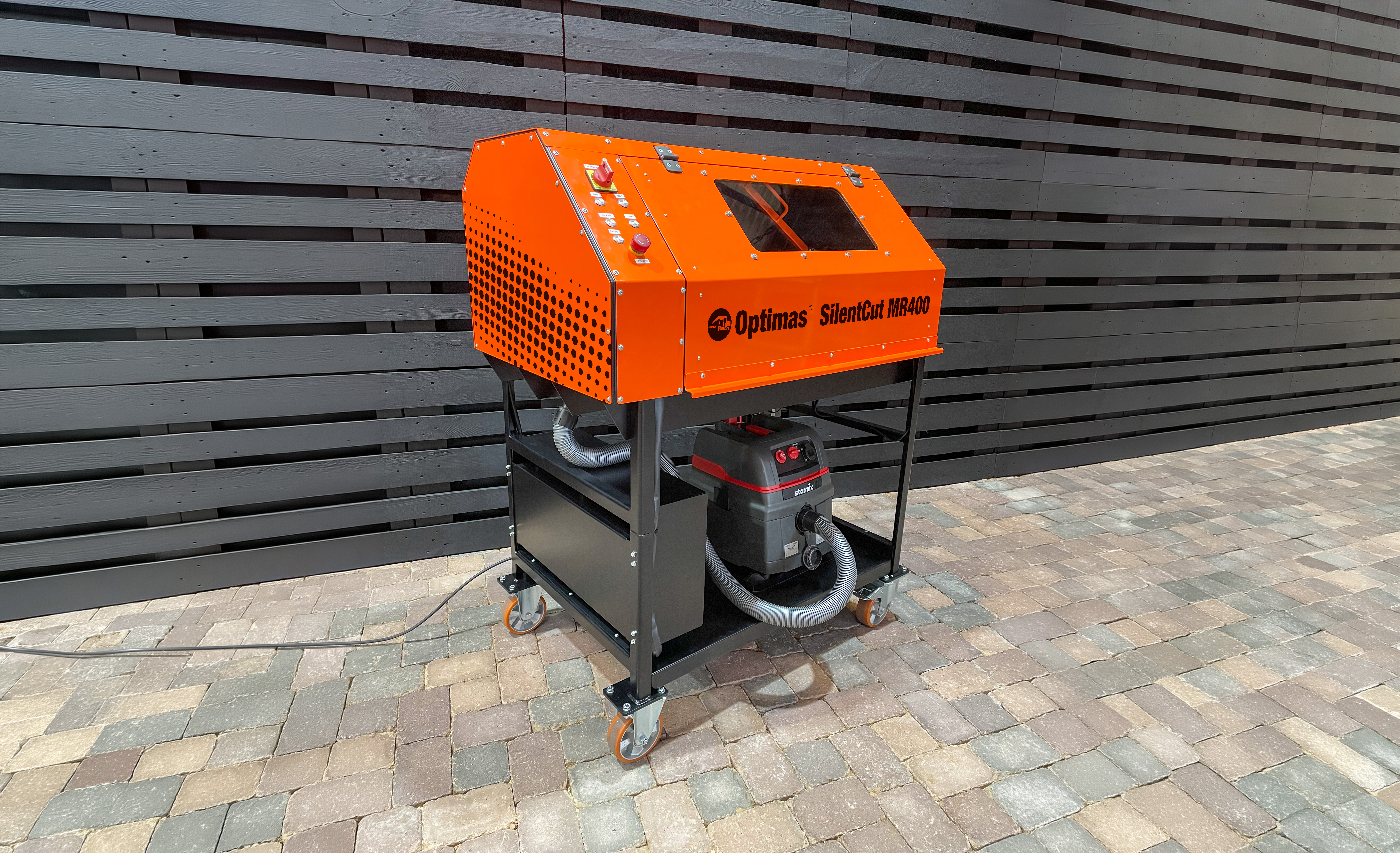 Optimas SilentCut MR400-Maschine mit orangefarbenem Gehäuse und schwarzem Sockel auf Steinboden – Optimas.