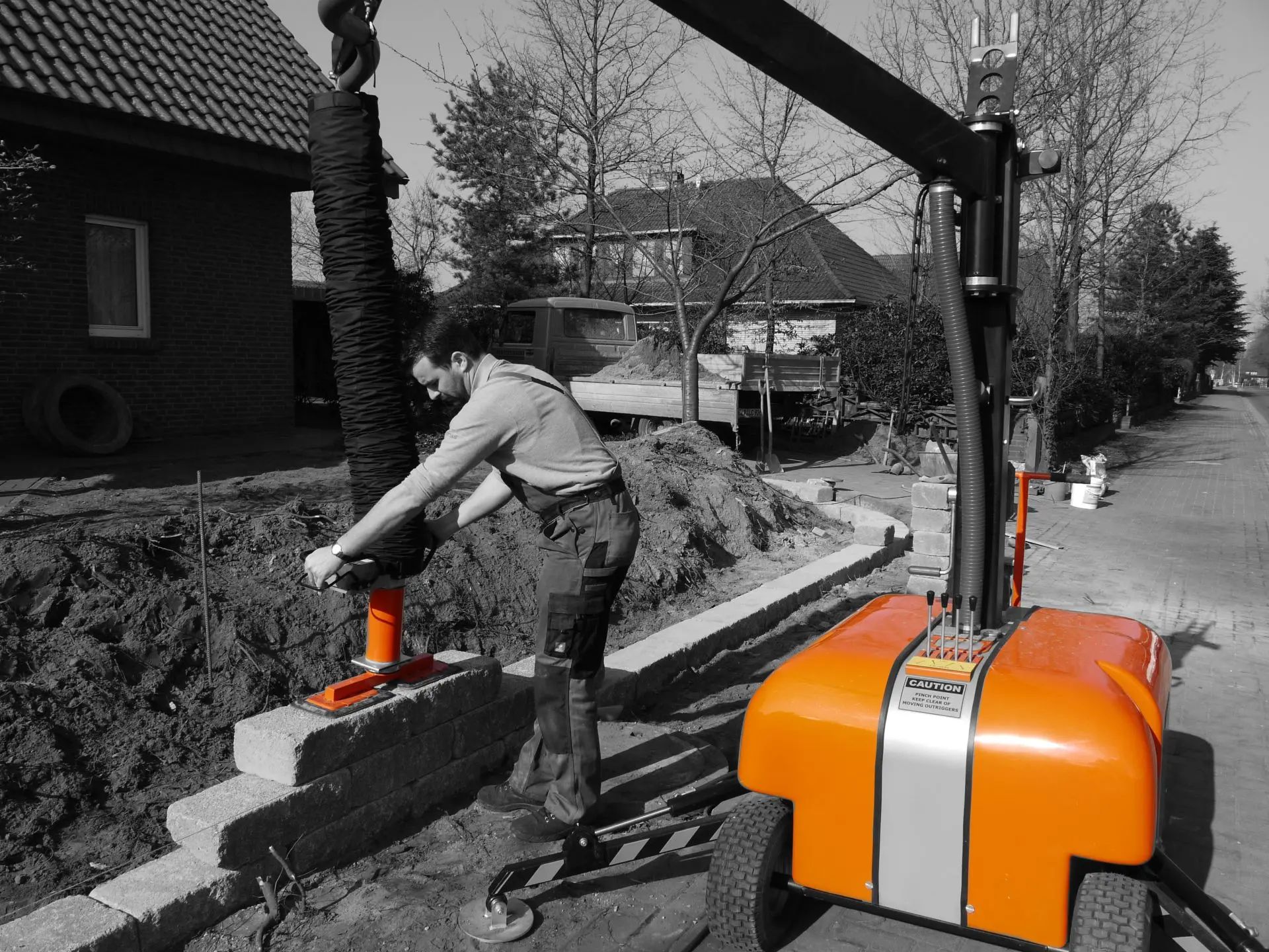 Ein Arbeiter bedient eine Baumaschine und hebt einen schweren Gegenstand auf einer Baustelle – Optimas.