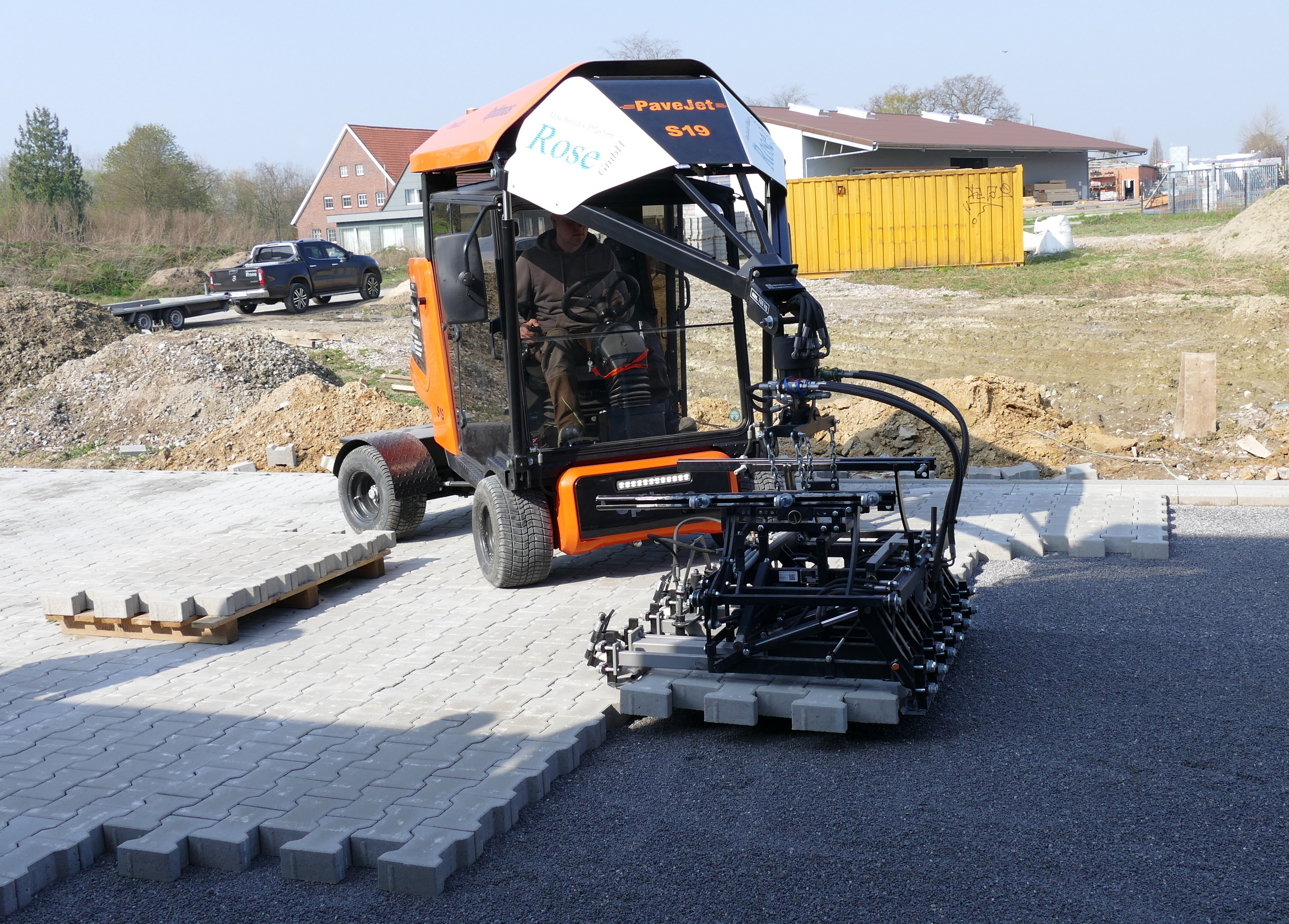 Die Pflastermaschine PaveJet S19 verlegt Verbundpflastersteine ​​auf einer Außenbaustelle und demonstriert automatisierte Pflastertechnologie und Effizienz – Optimas.