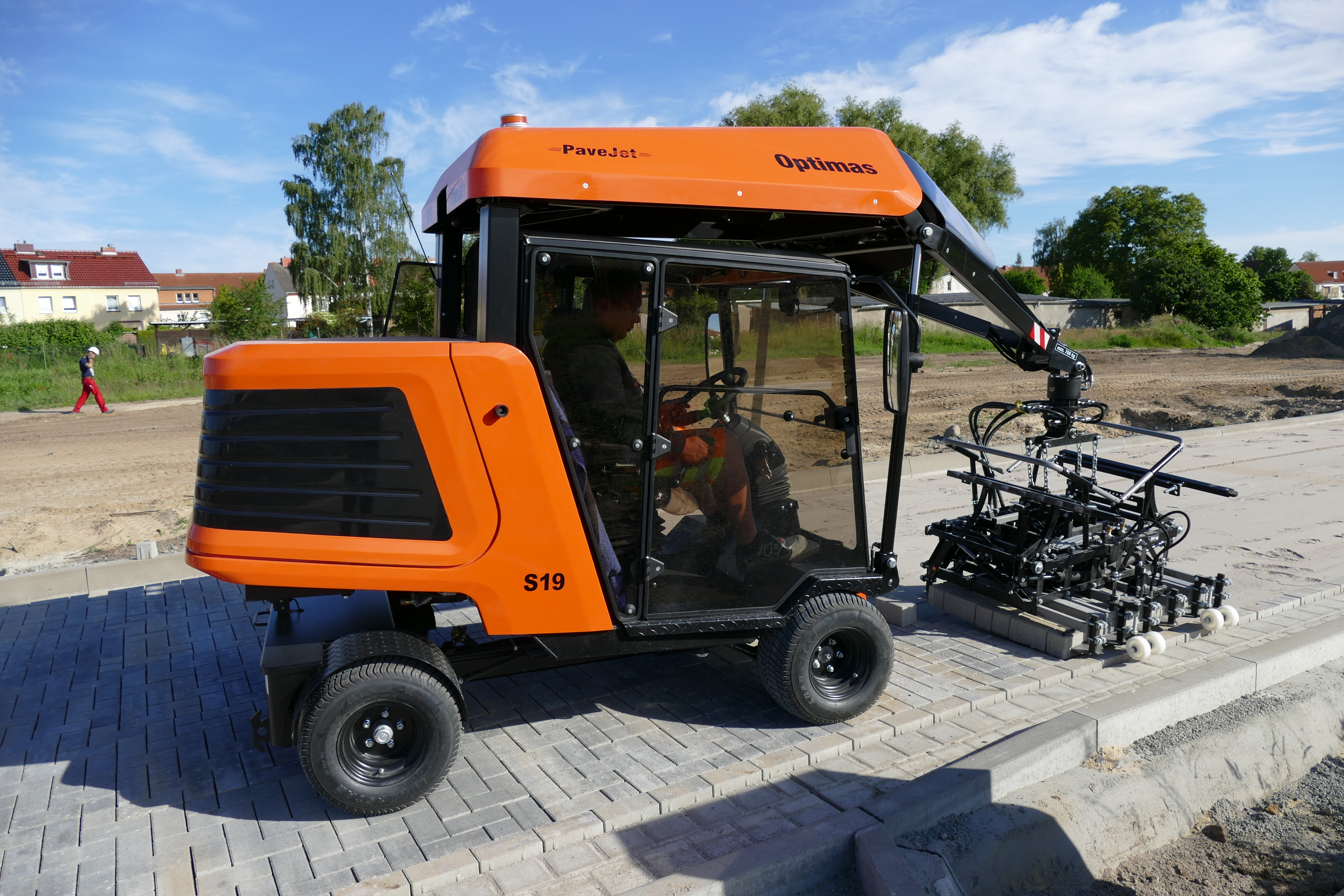 PaveJet Optimas S19 Pflastermaschine verlegt Pflastersteine ​​mit einem Arbeiter in der Kabine auf einer Baustelle und sorgt für Effizienz – Optimas.